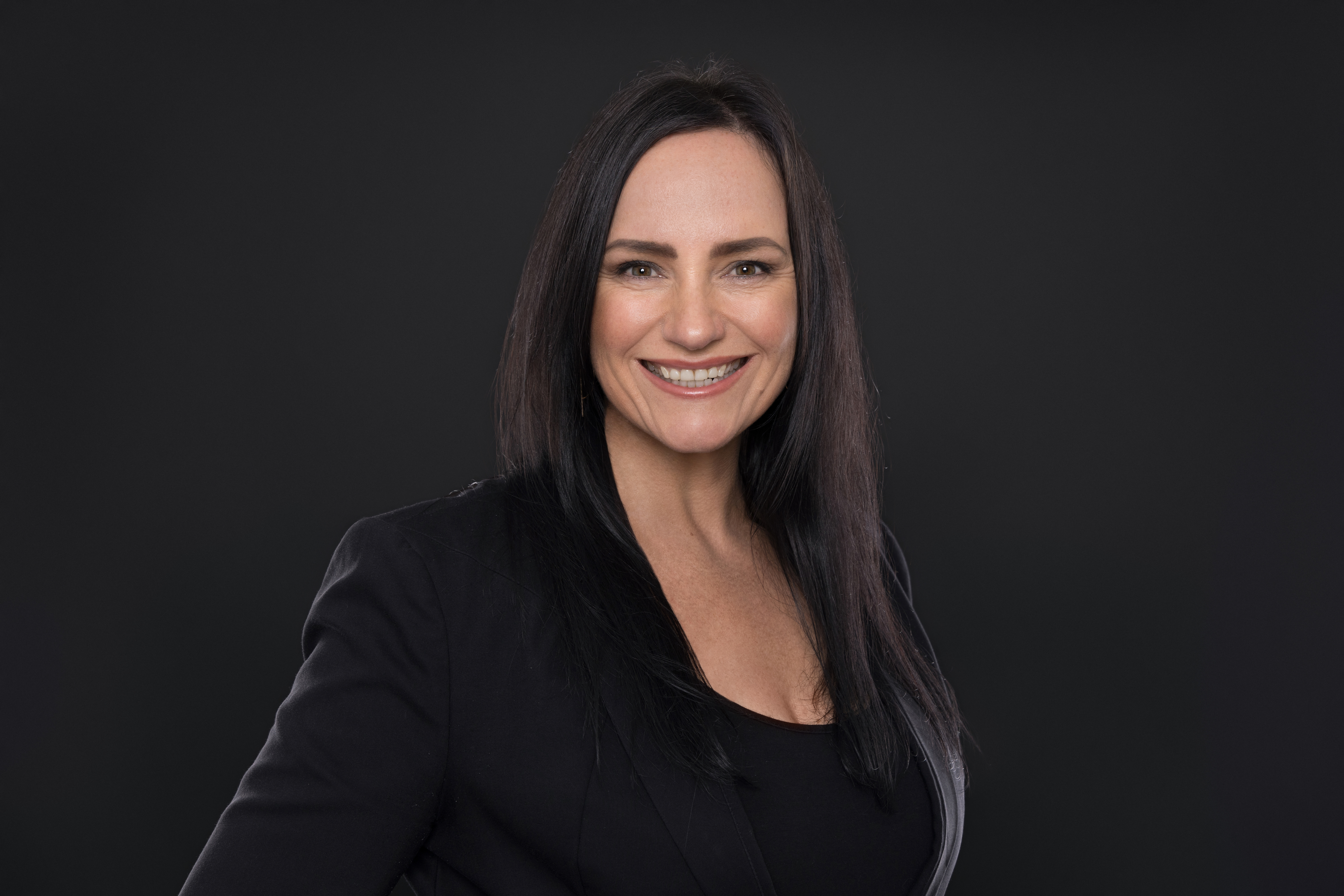Professional corporate headshot on dark background — the kind of high-quality source material AI content builds from