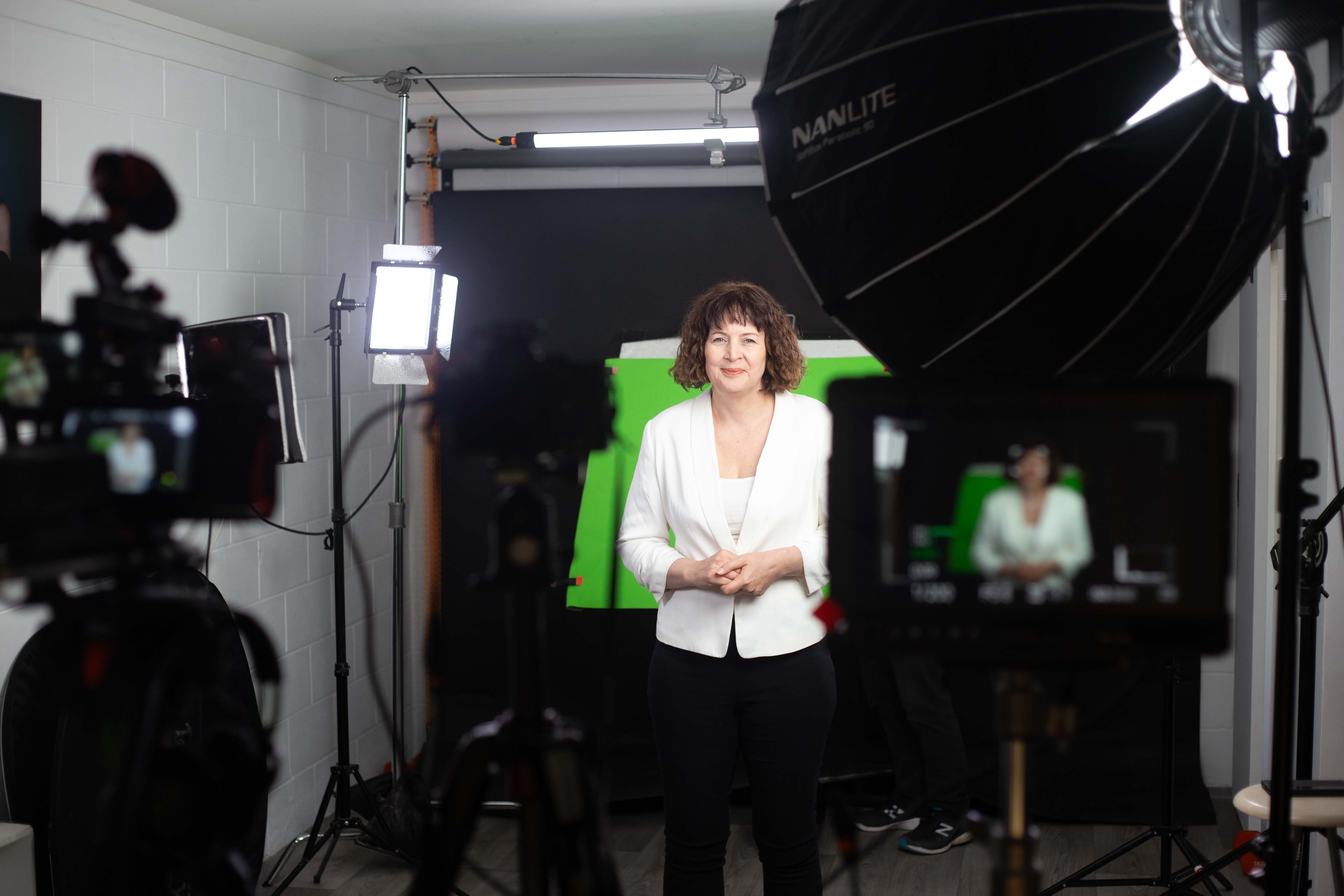 Client being filmed in a professional digital twin studio setup with green screen and Nanlite lighting